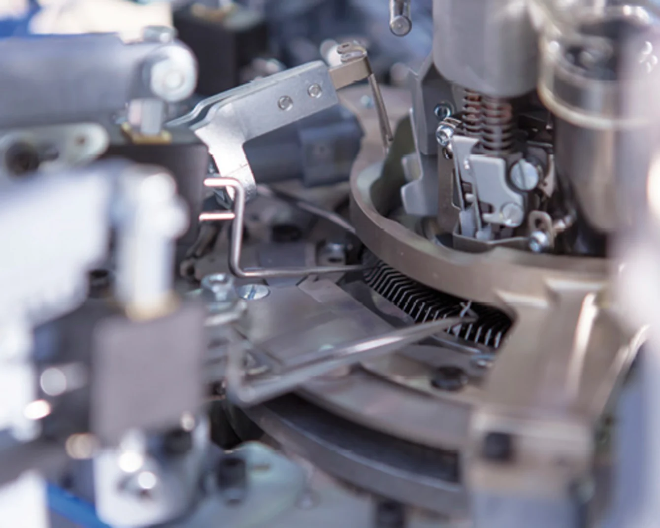 Close-up of intricate machinery with metal gears, levers, and springs, showcasing a complex mechanical system in silver and gray tones.