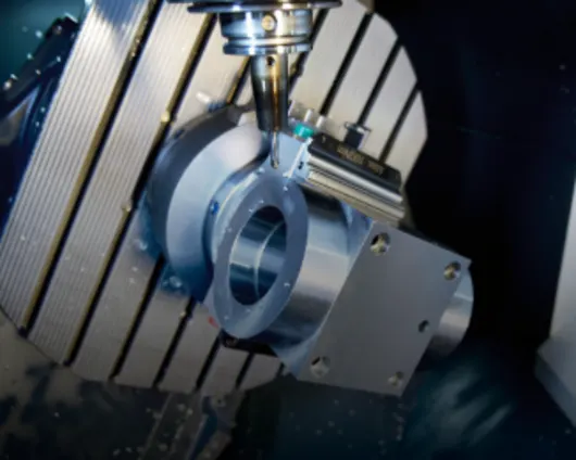 CNC milling machine cutting a metal workpiece on a slatted table with precision tooling and blue coolant visible