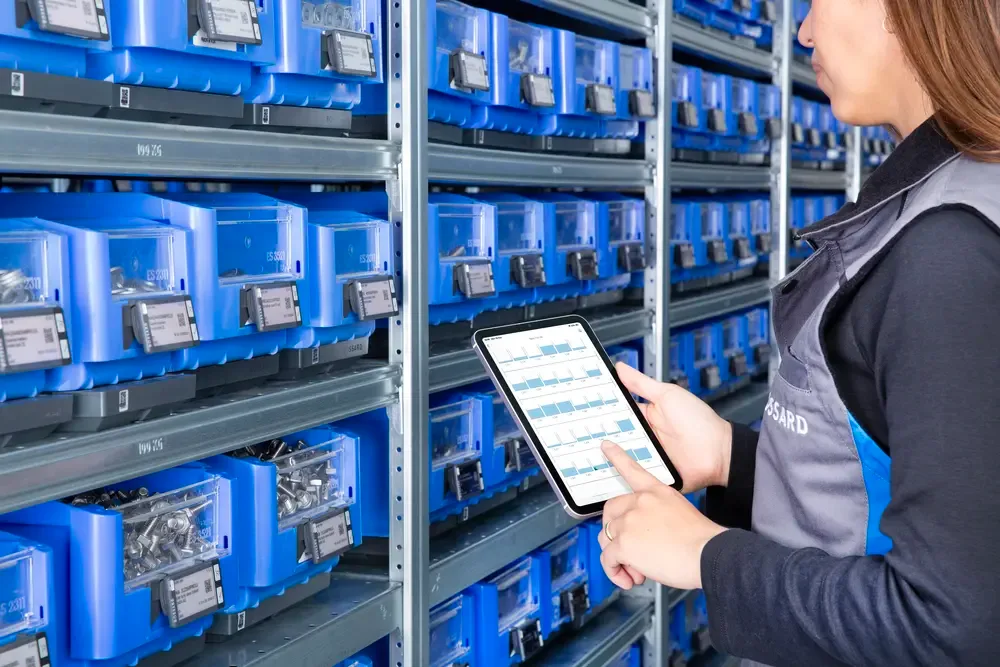 一个人在C类零件箱前用平板电脑查看库存信息。