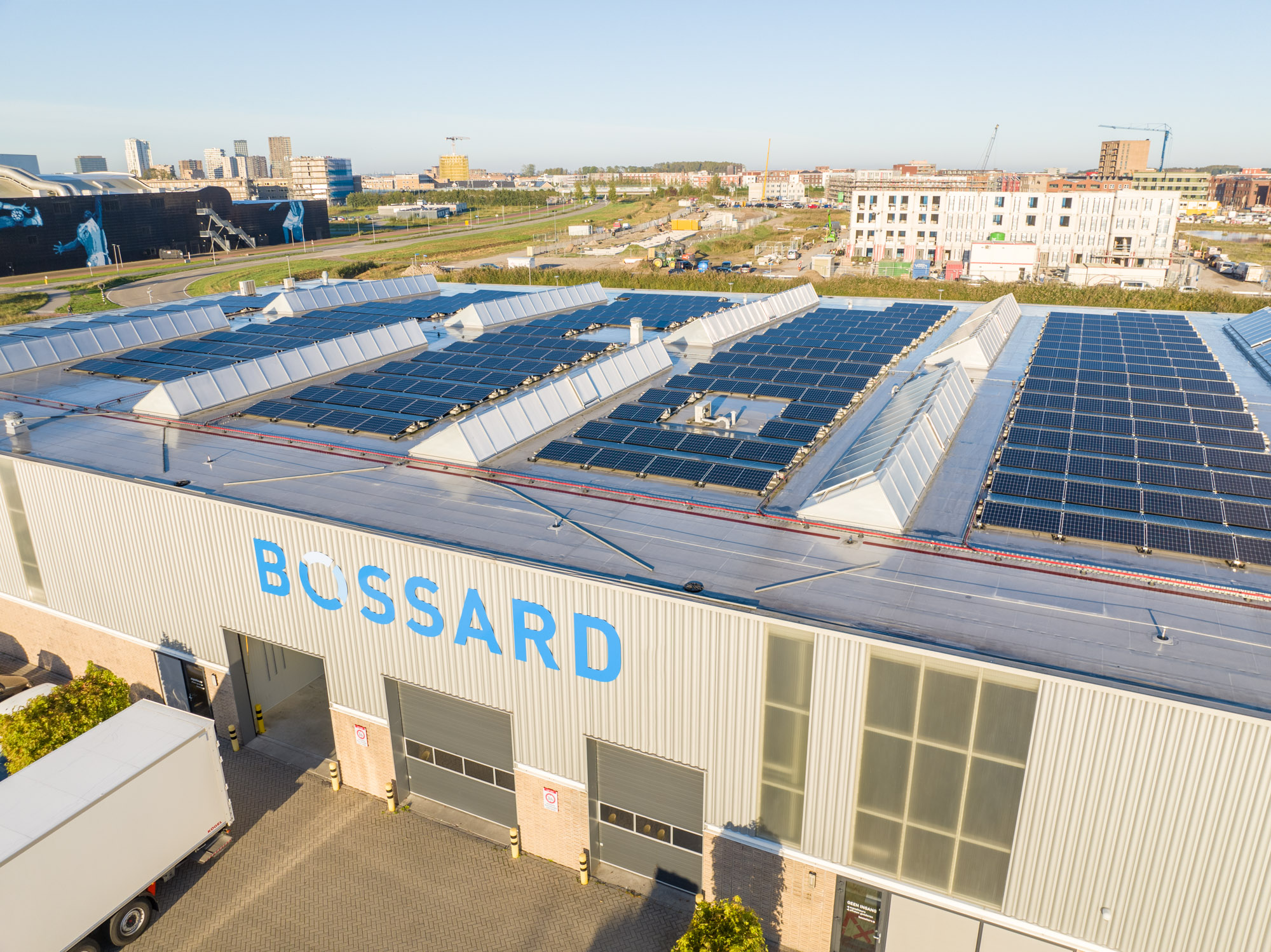 俯瞰荷兰Bossard业务单元，展示了带有太阳能板的建筑及周围的户外区域。