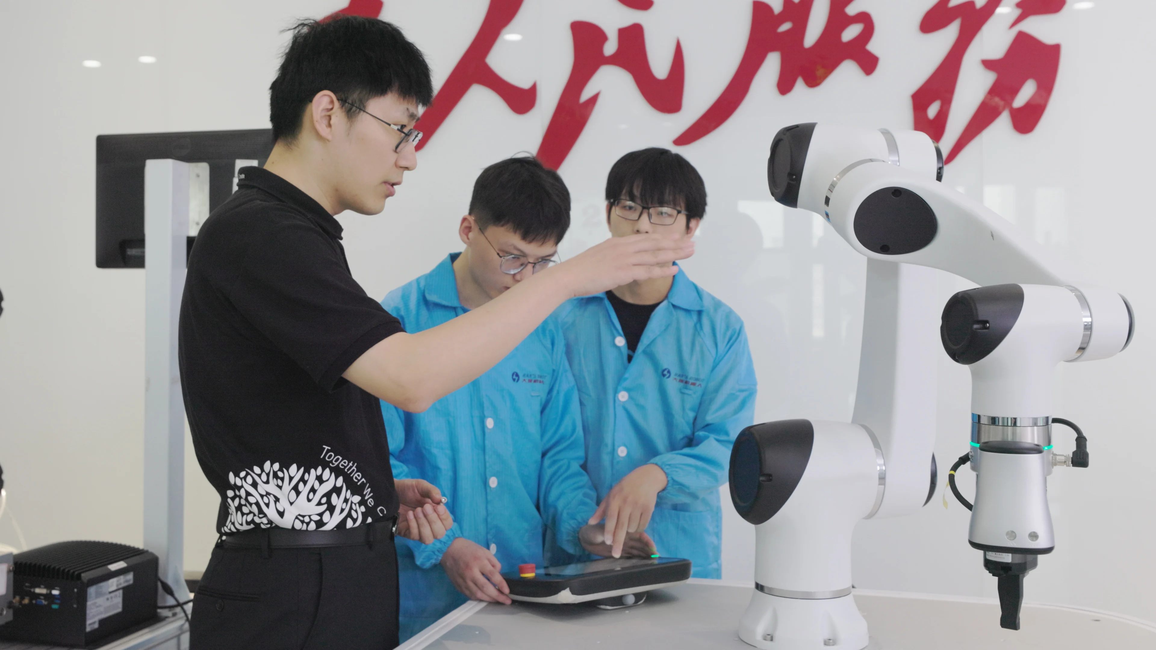 三位技术人员在实验室中分析白色机器人机械臂,展示机器人研发与精密工程能力
