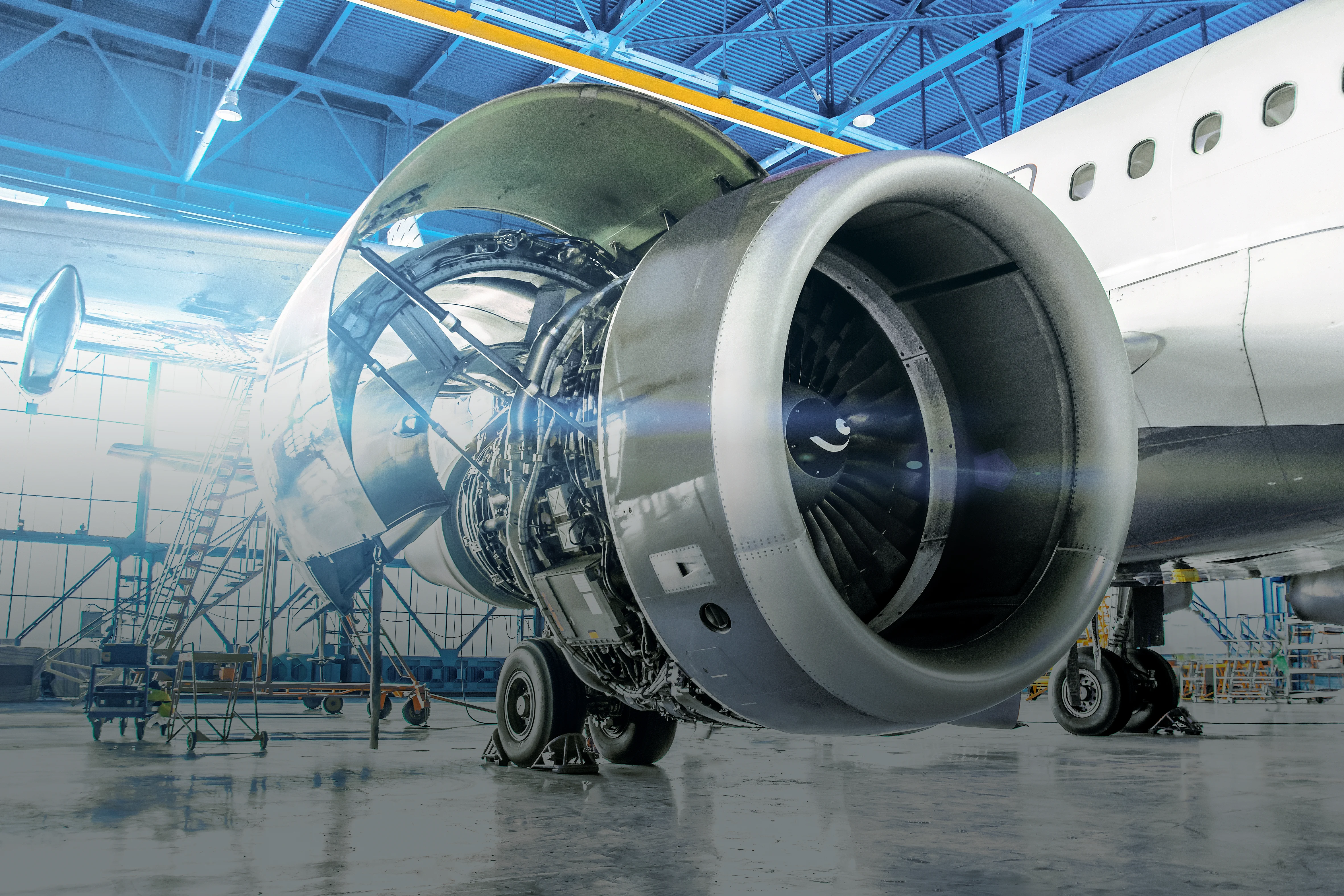 A close-up of an airplane engine situated in a hangar with blue walls, highlighting its mechanical features.