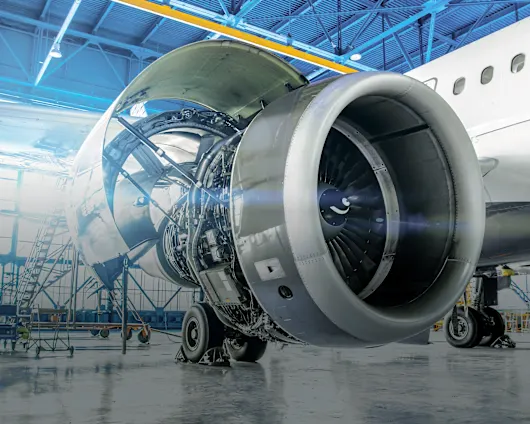 A close-up of an airplane engine situated in a hangar with blue walls, highlighting its mechanical features.