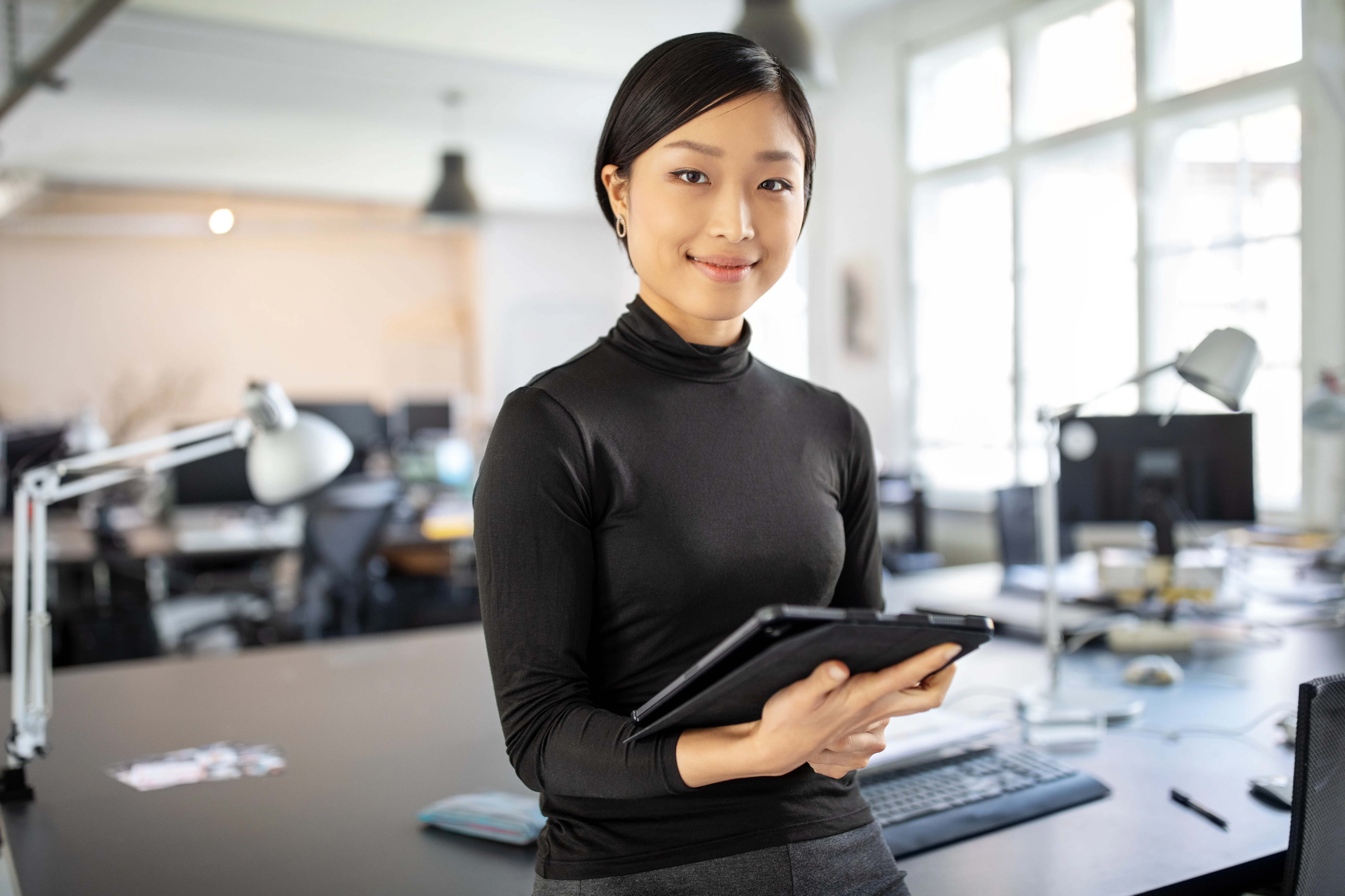 Female designer in her office, holding a tablet in her hands
