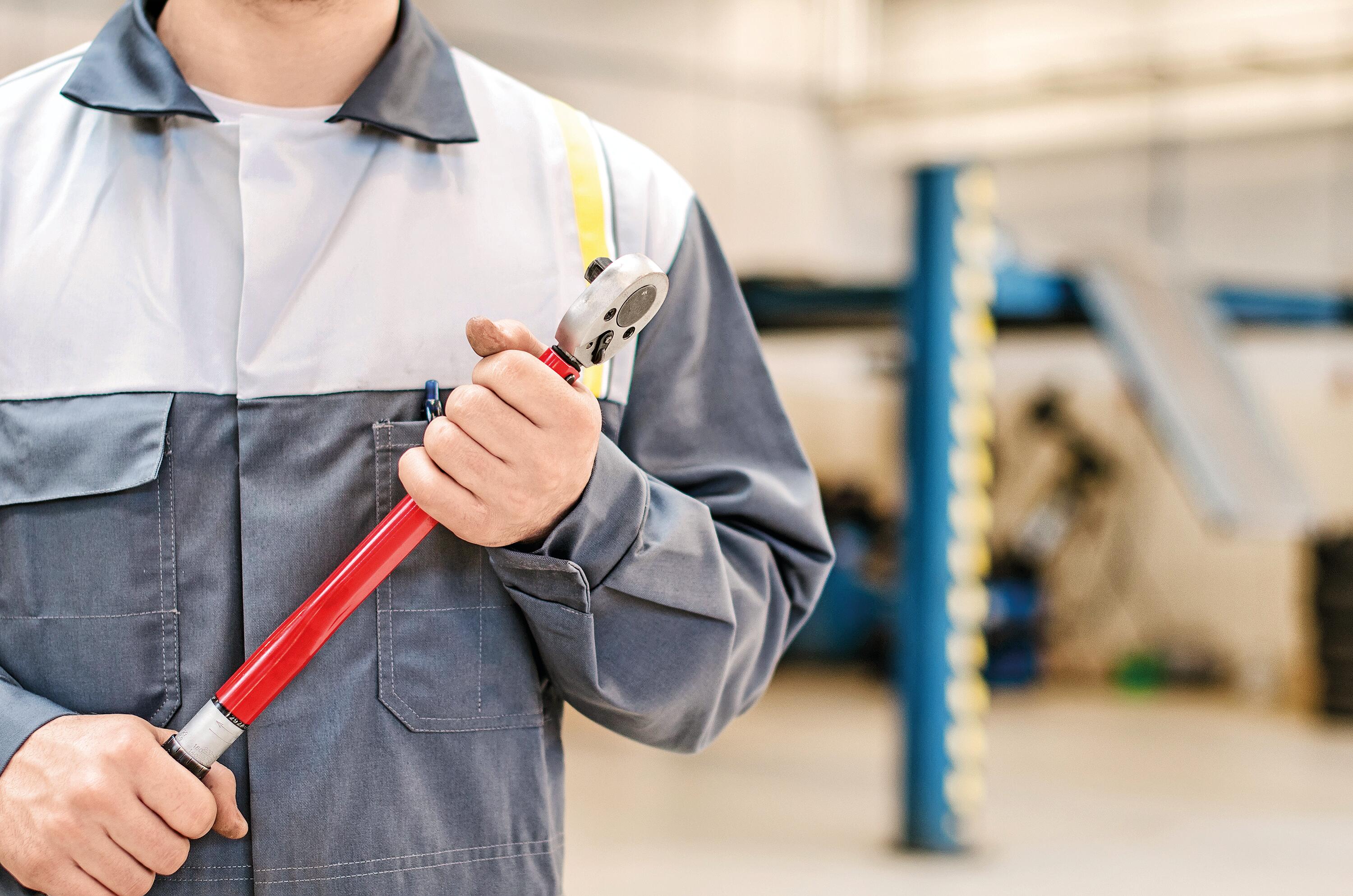 Mechanic with torque wrench at auto repair shop.