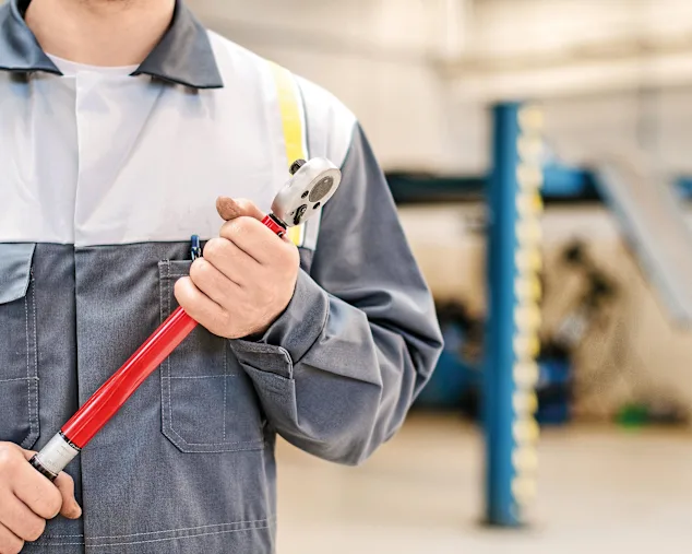 Mechanic with torque wrench at auto repair shop.