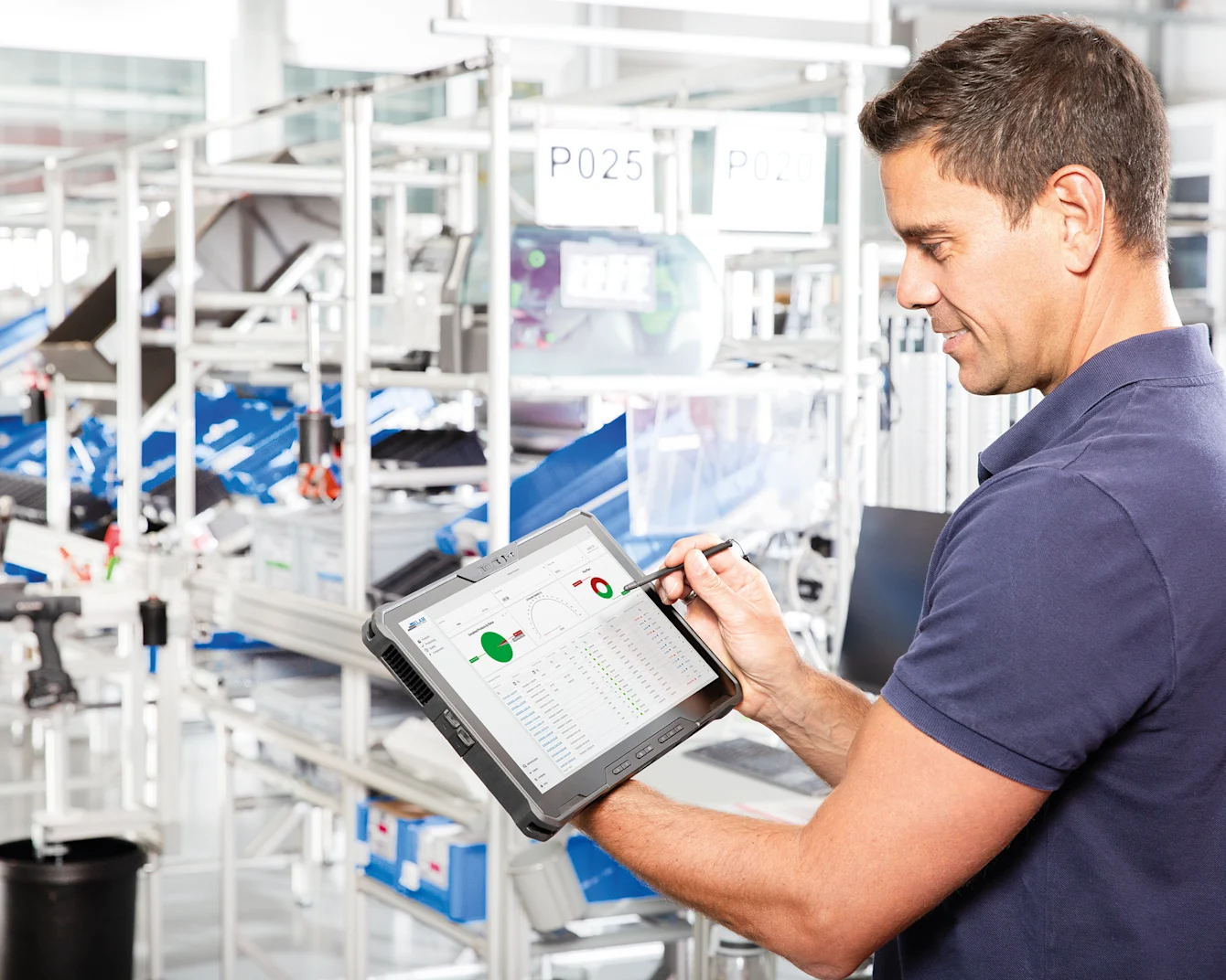 Smart Factory Assembly Guy with Tablet in his hands looking at the Dashboard with realt-time data