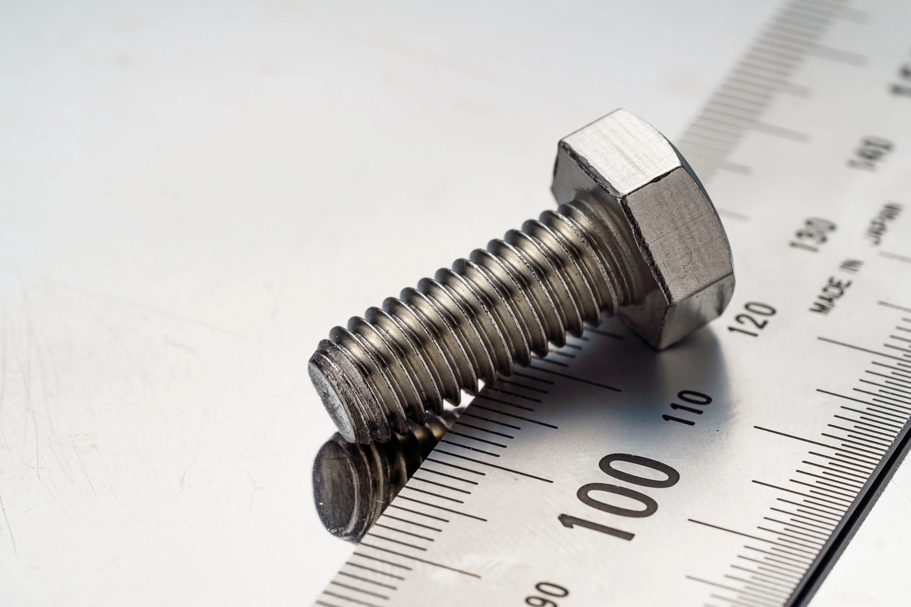 
金属板上的钢螺栓特写与尺子