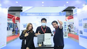 Three Bossard employees at a trade fair stand in front of a booth marked "Smart Factory & Fastening Solutions," featuring Bossard's branding.