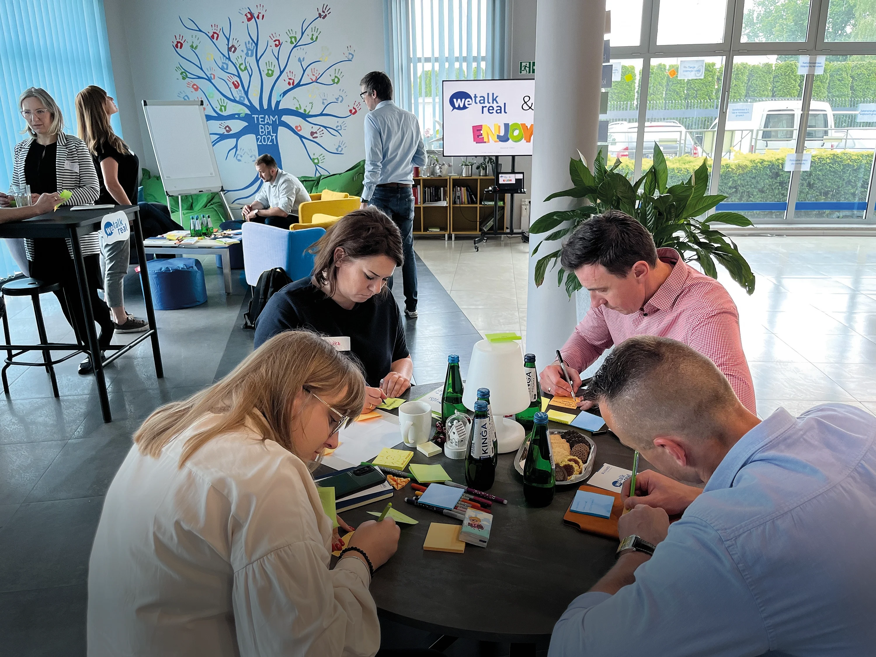 A group of individuals collaborates at a table, surrounded by colorful sticky notes, engaged in a brainstorming session.