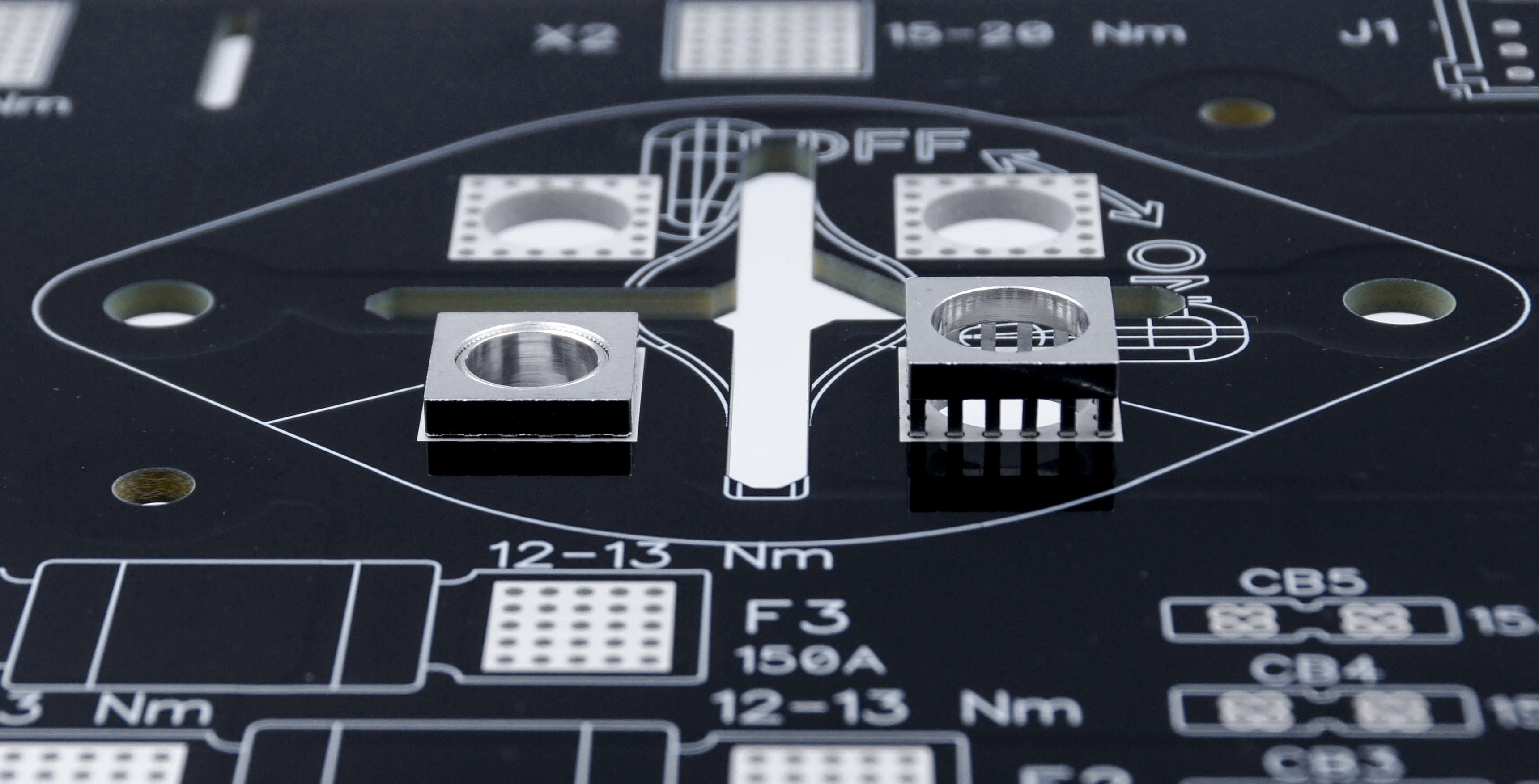 Close-up of a black PCB with MTCON power elements, three already pressed in, one still to be assembled