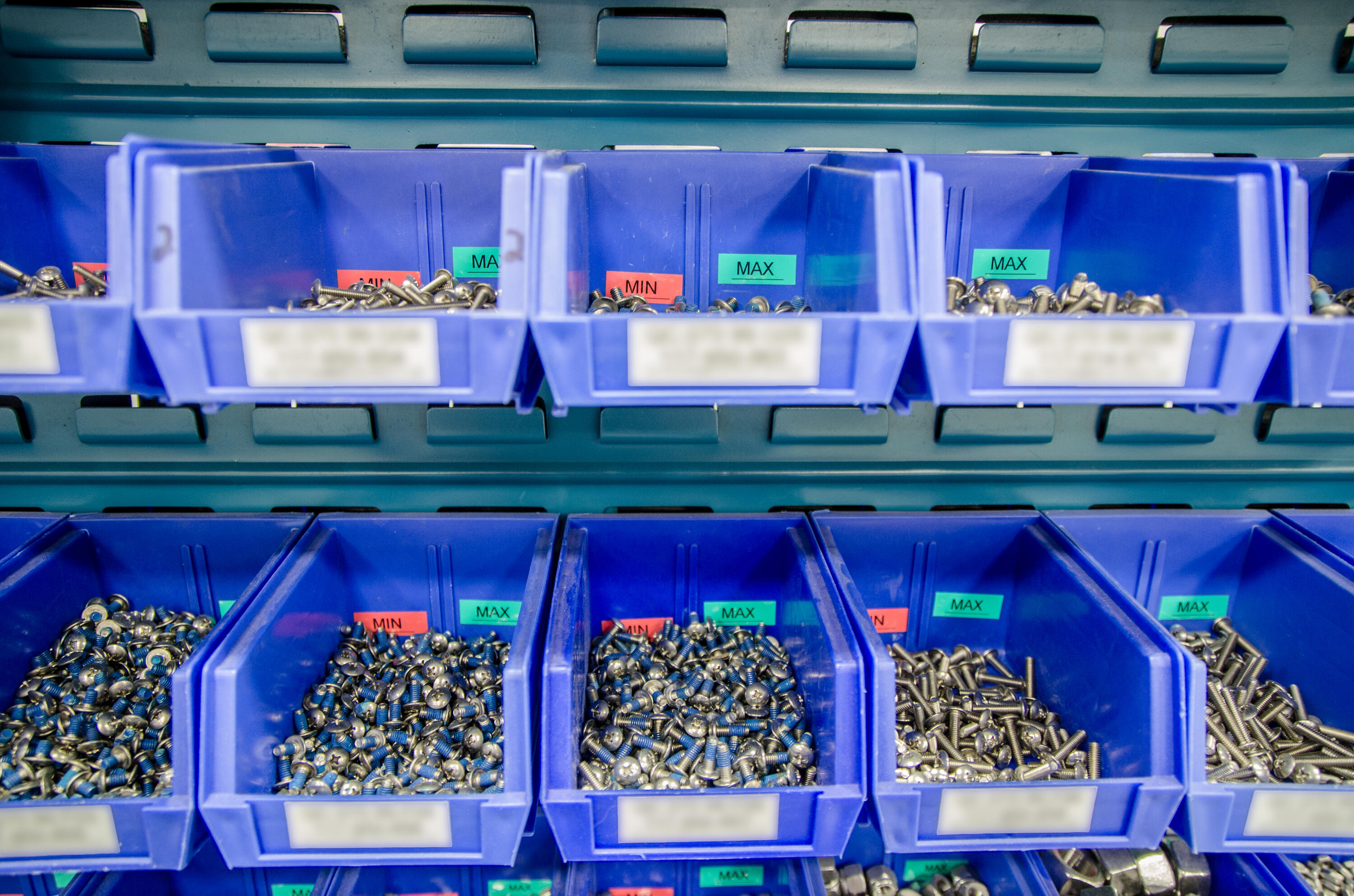 Blue plastic storage bins filled with various nuts, bolts, and fasteners organized in compartments for hardware storage.