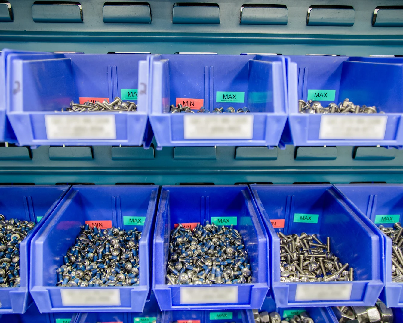 Blue plastic storage bins filled with various nuts, bolts, and fasteners organized in compartments for hardware storage.