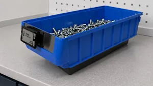Blue plastic storage bin filled with fasteners, on gray work surface.