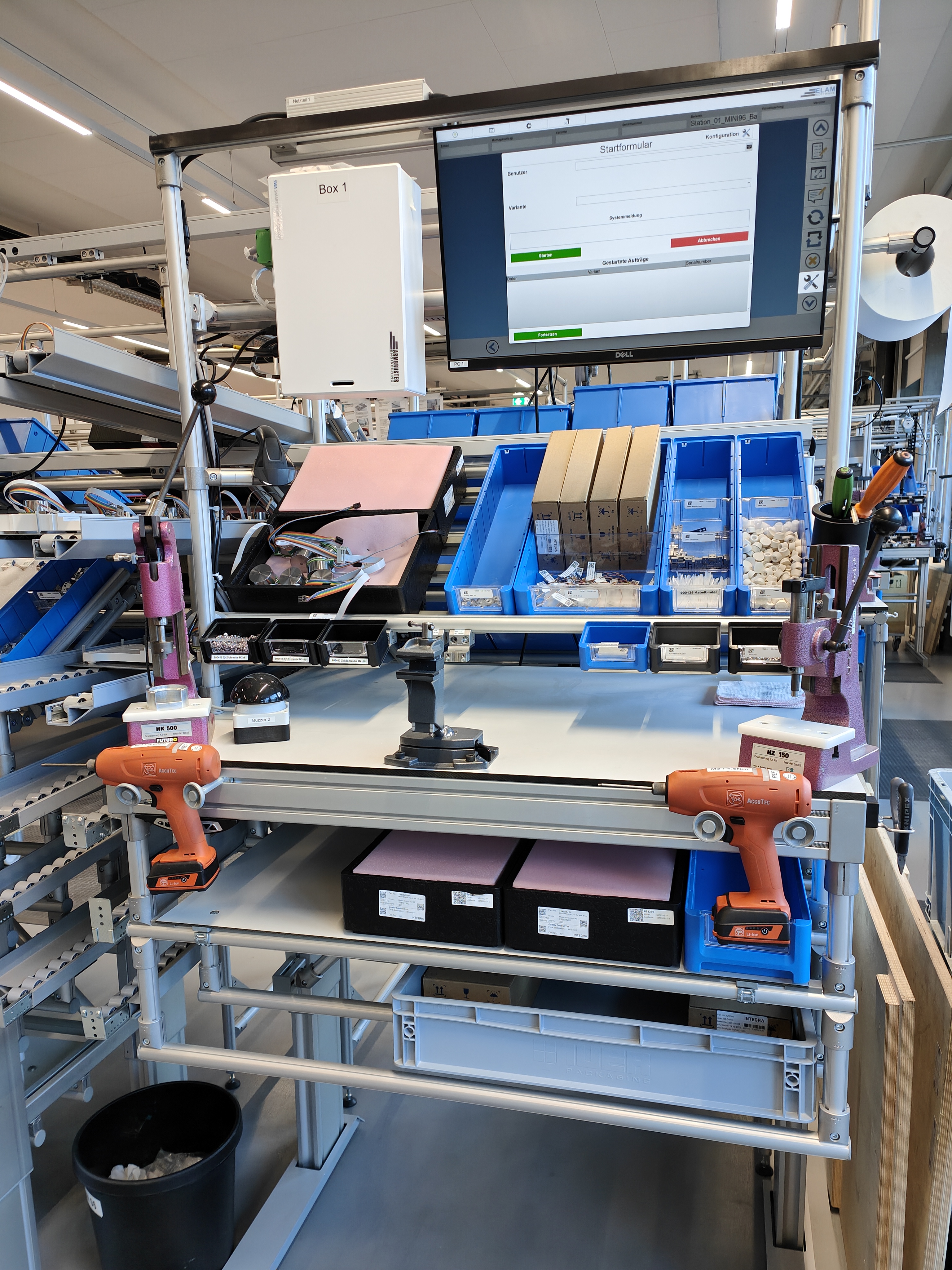 Ein Computerbildschirm auf einem Tisch in einer modernen Arbeitsstation mit Werkzeugen in einer Fabrik.