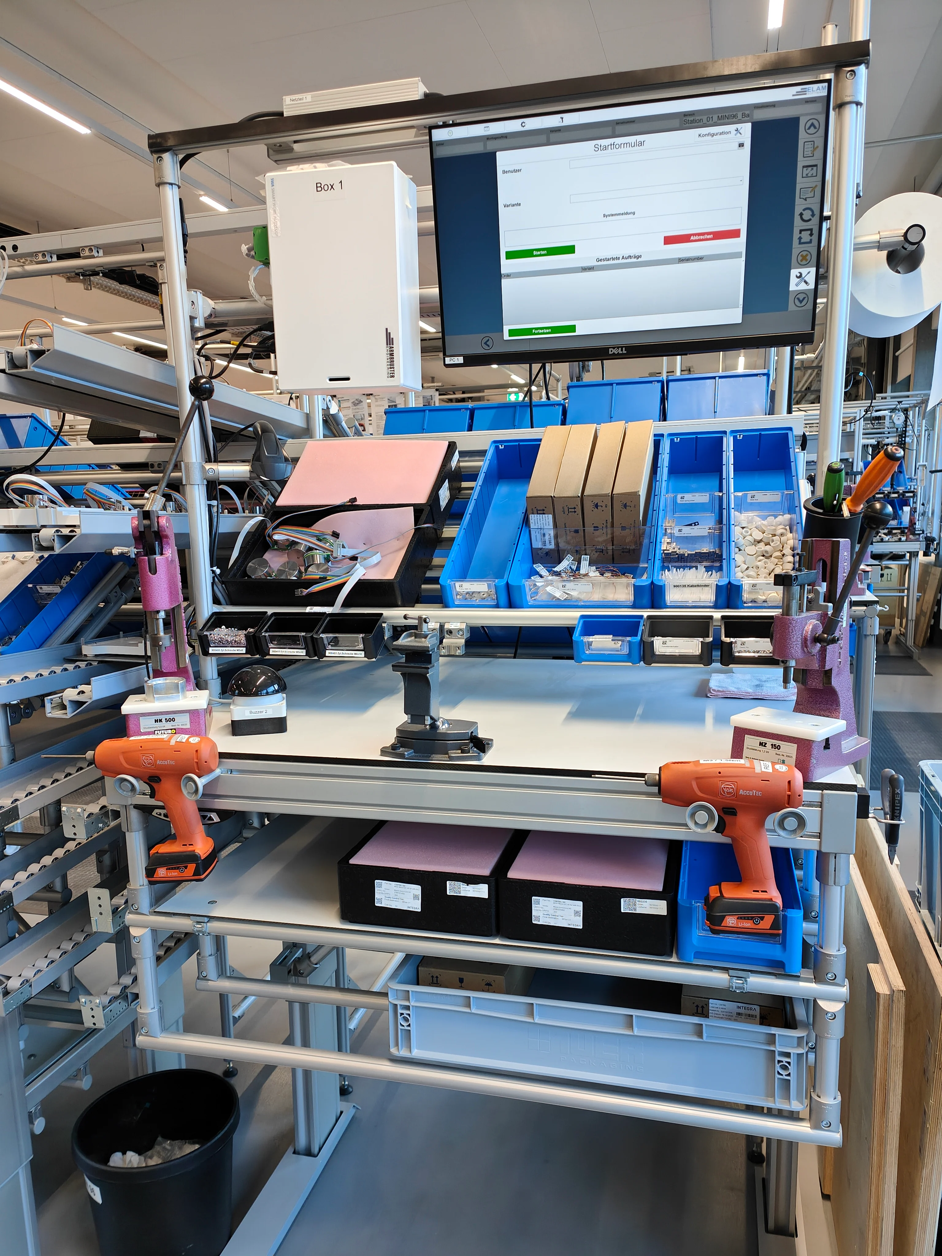 一台电脑屏幕放在工厂现代工作站的桌子上,旁边有工具。