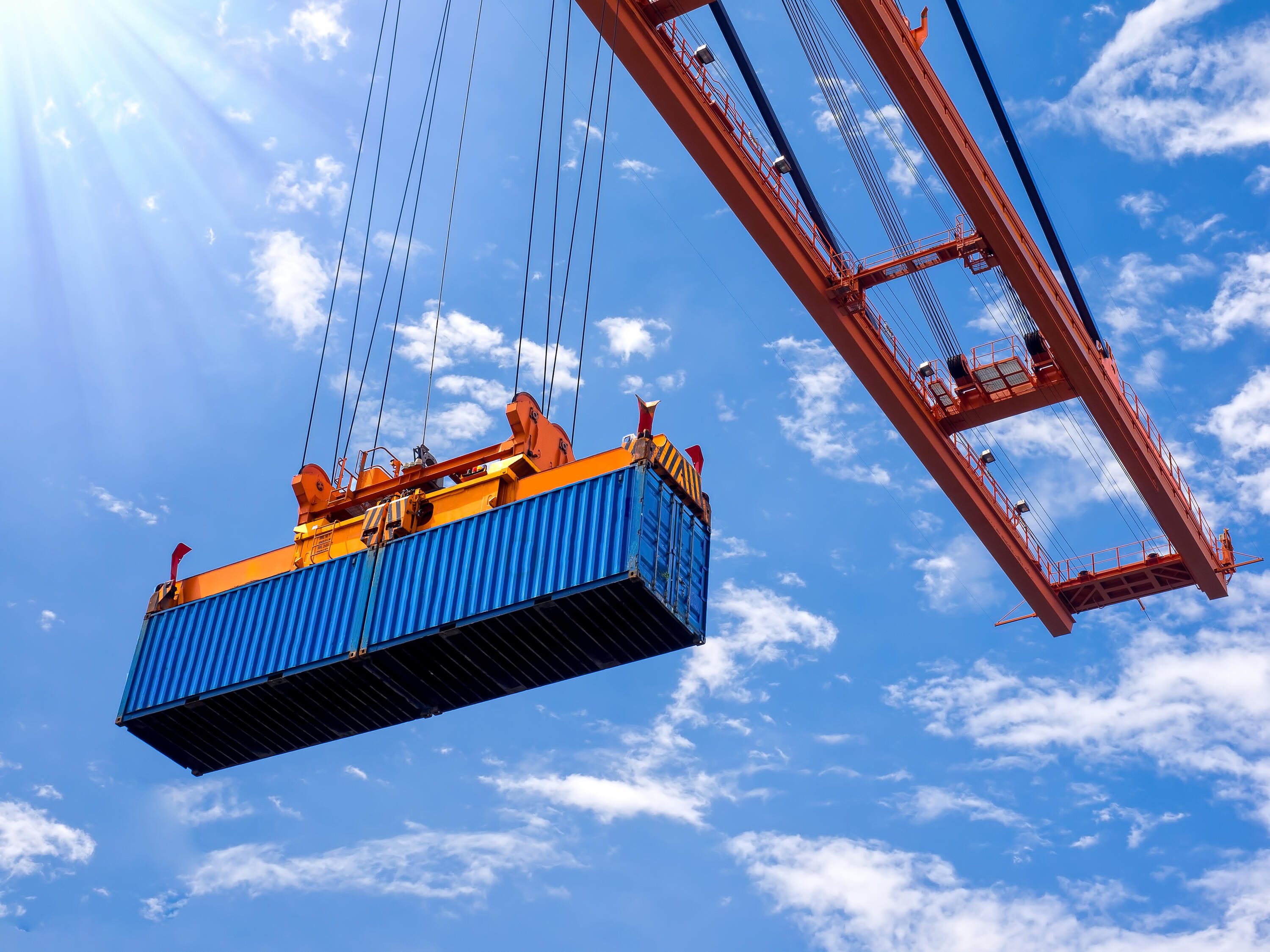 Low angle view of a container on a crane against blue sky.