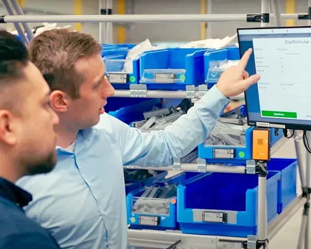 Two men at a screen point to the elam solutions shown