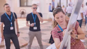 A woman is actively writing on a whiteboard, demonstrating engagement in a learning or brainstorming session.