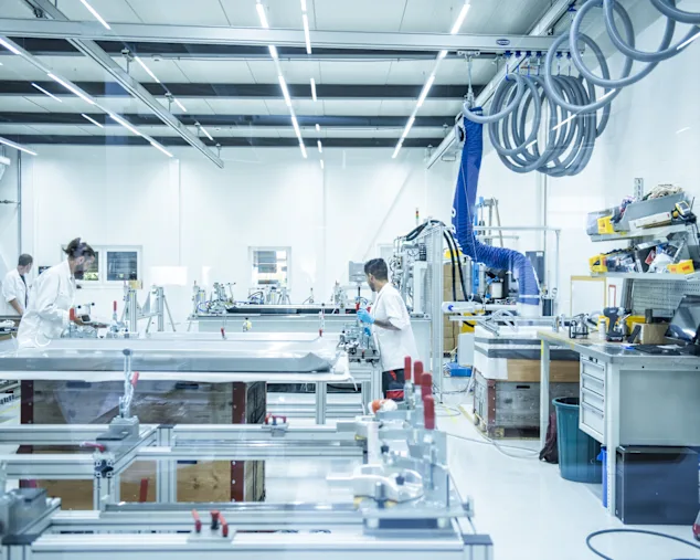 3 workers in an isolated assembly room, with controlled environment.