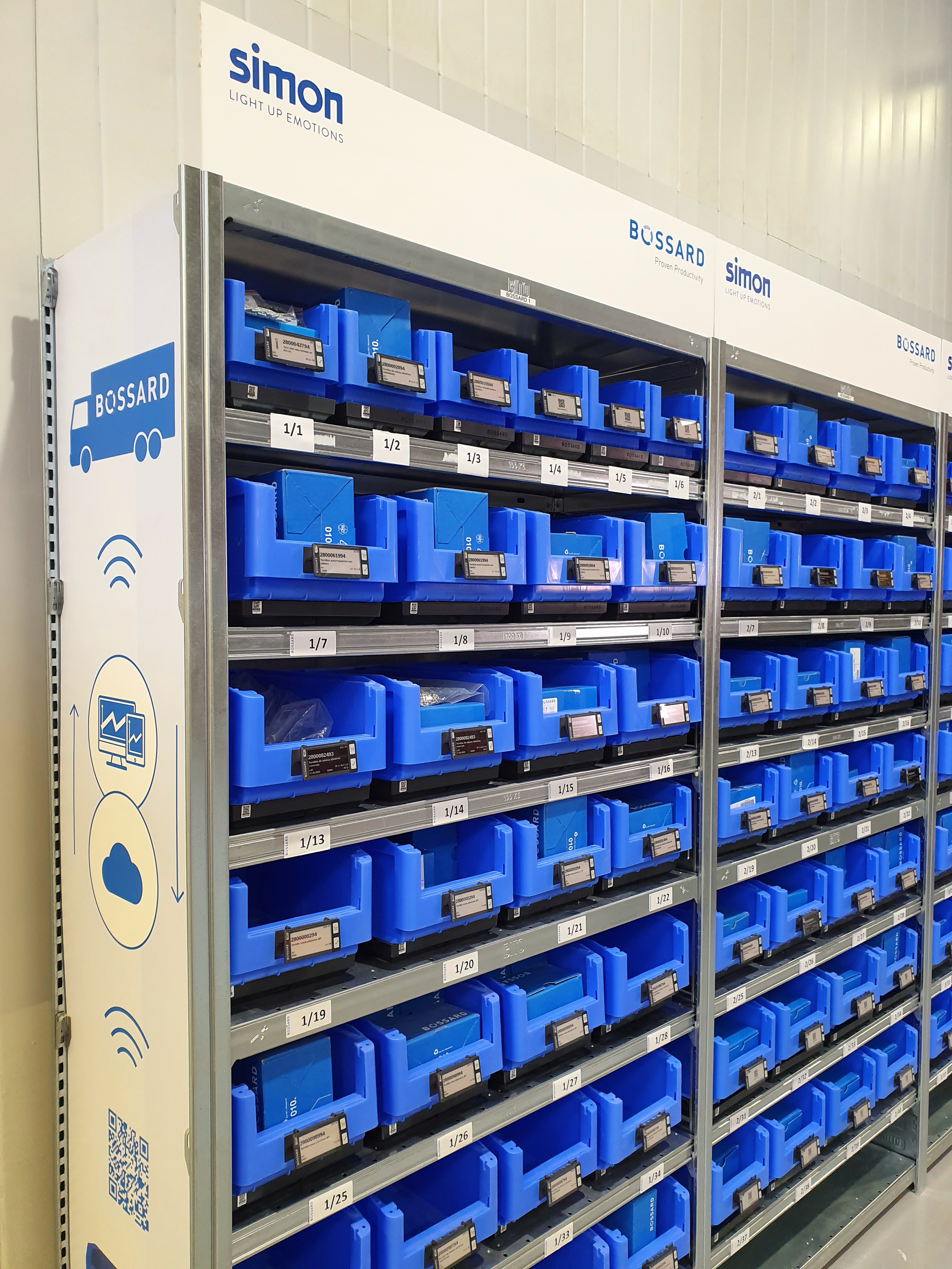 Shelves filled with organized blue bins, each labeled with numbers, in a storage area with "Simon" and "Bossard" branding.