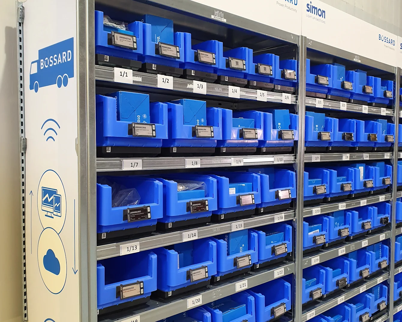 Shelves filled with organized blue bins, each labeled with numbers, in a storage area with "Simon" and "Bossard" branding.