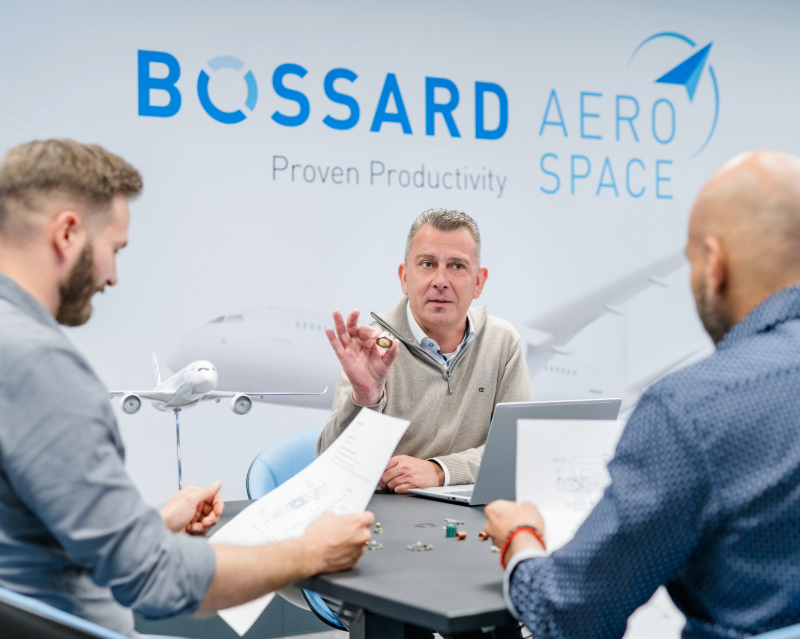3人在Bossard航空航天墙背景下审查设计和紧固件