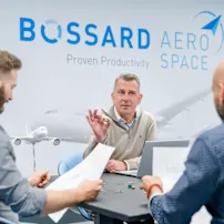 3 people reviewing design and fasteners with Bossard Aerospace wall background