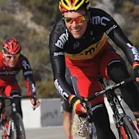 Three men dressed in red and black jerseys with BMC logo cycling together, highlighting their shared passion for biking.