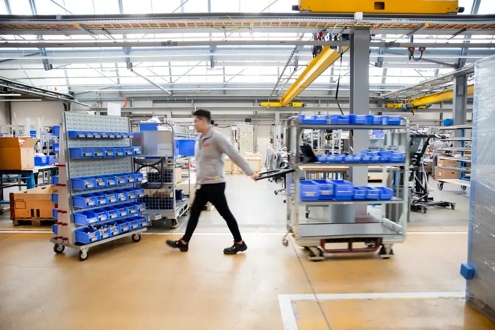 Milk runner walking through modern warehouse facility to refill bins on the shop floor