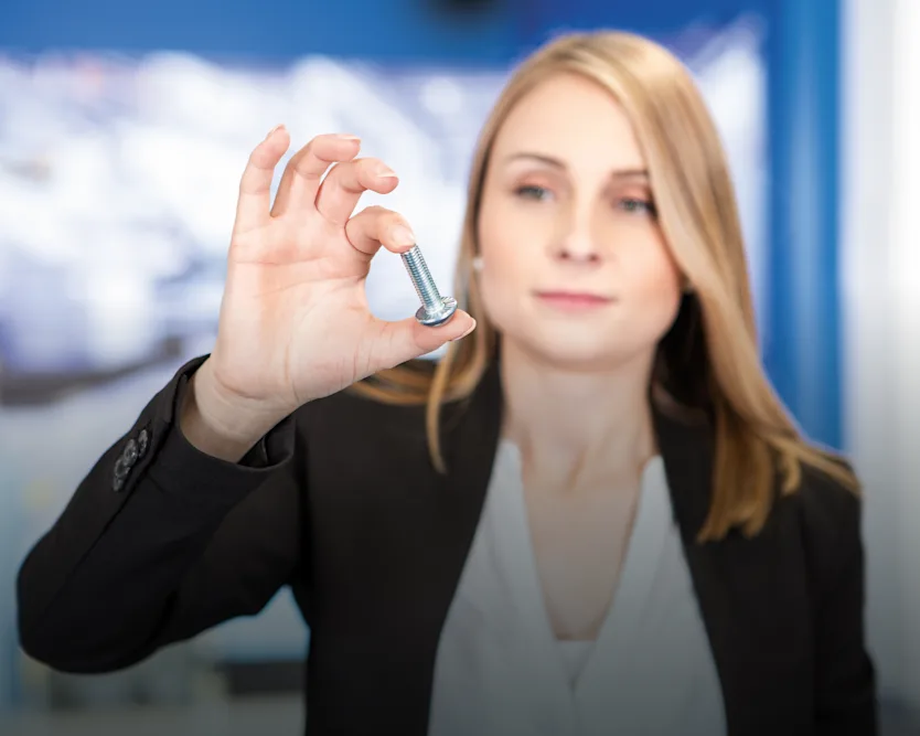 Woman in business attire holding a screw in her hand