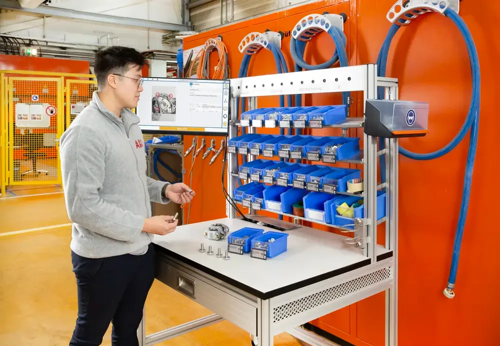 Assembly worker at workstation with SmartLabel Cloud bins and work instruction displayed on screen.