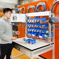 Assembly worker at workstation with SmartLabel Cloud bins and work instruction displayed on screen.