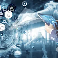 A person in a suit holds a tablet displaying technical diagrams, while an industrial environment with robotics is blurred in the background. Digital icons representing industrial facilities, energy, automation, and data analytics are overlaid on the image.