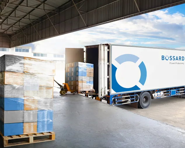 White Bossard delivery truck being loaded with wrapped pallets in warehouse loading bay.