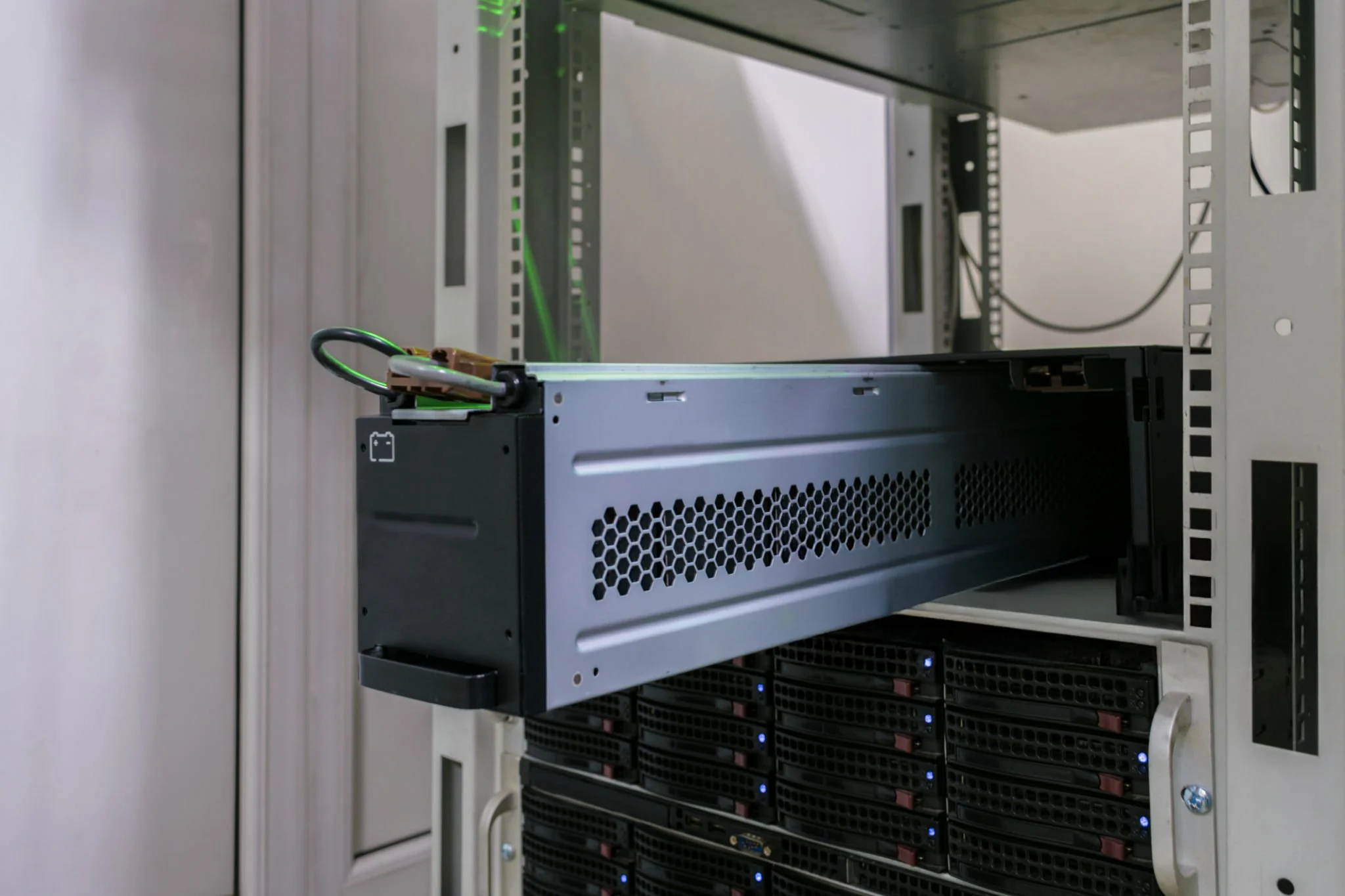 白色服务器机柜内的服务器硬件，包含黑色和灰色的机架式设备、通风格栅以及蓝色 LED 指示灯。