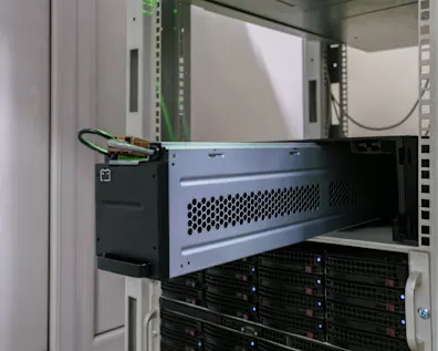 Server hardware with black and gray rack-mounted equipment, ventilation grilles, and blue LED lights in a white server cabinet
