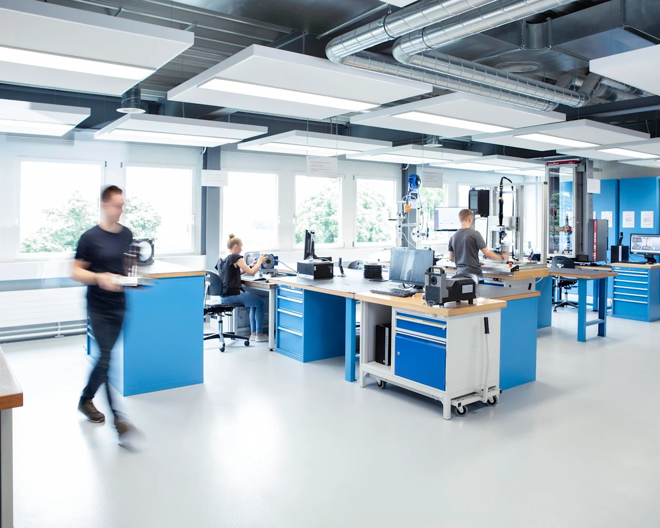 Three engineers collaborating on various tests in a well-equipped laboratory, with a clear view of both the team and the testing equipment.