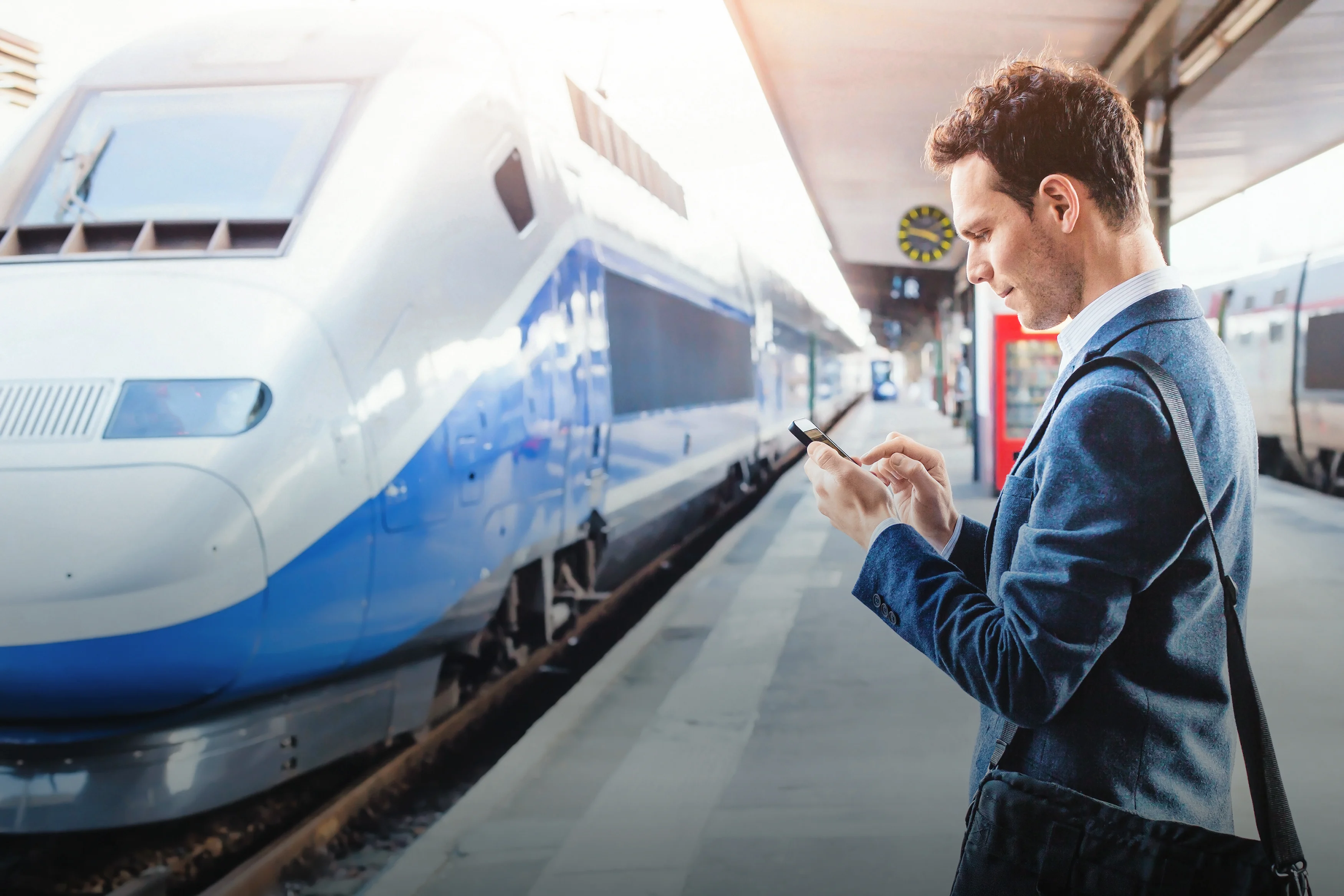 A man on a railway station using an electronic device