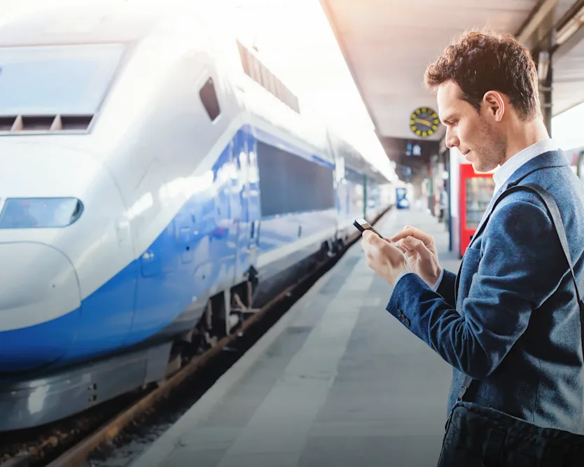 A man on a railway station using an electronic device