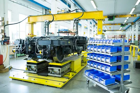 In the assembly hall, a railway running gear is surrounded by equipment and a mobile trolley fitted with SmartBins for efficient material handling