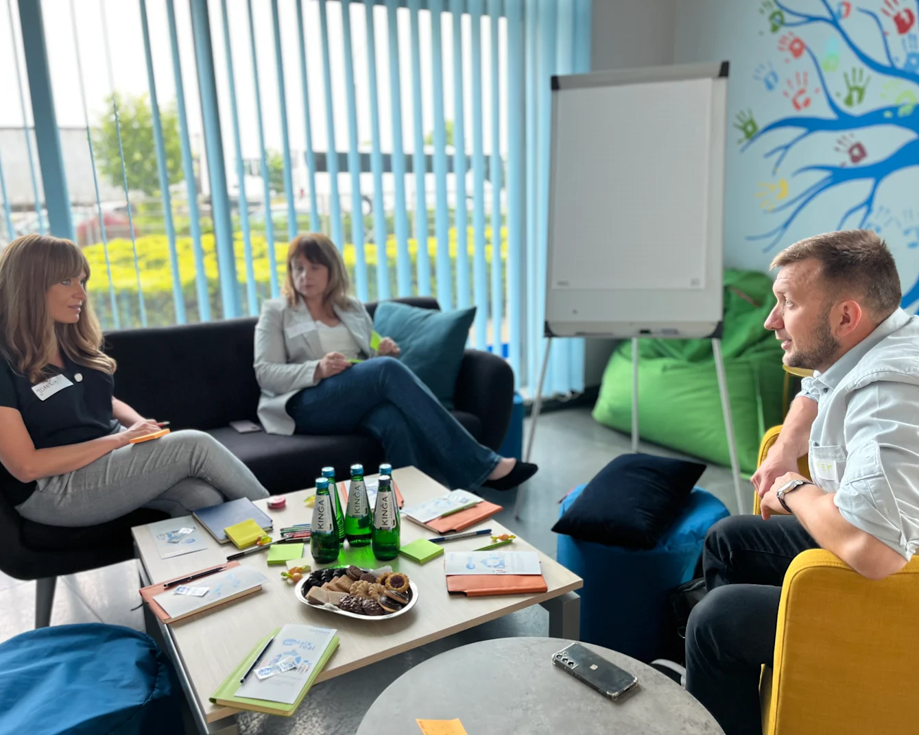A group of individuals gathered around a table in a room adorned with vibrant, colorful walls.