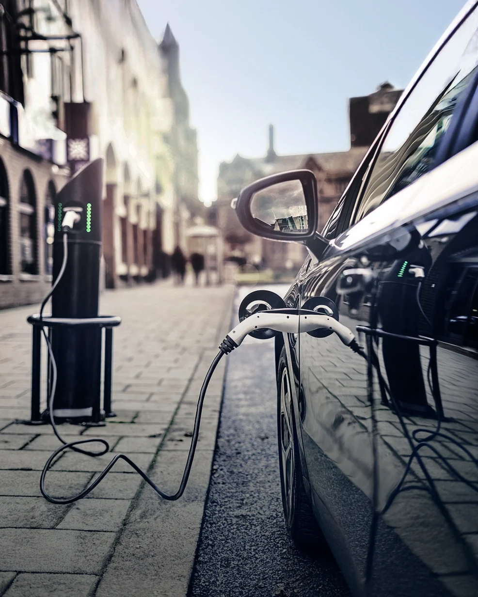 Electric Car standing on the roadside being charged at a charging station in the city.