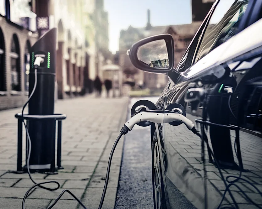 Electric Car standing on the roadside being charged at a charging station in the city.