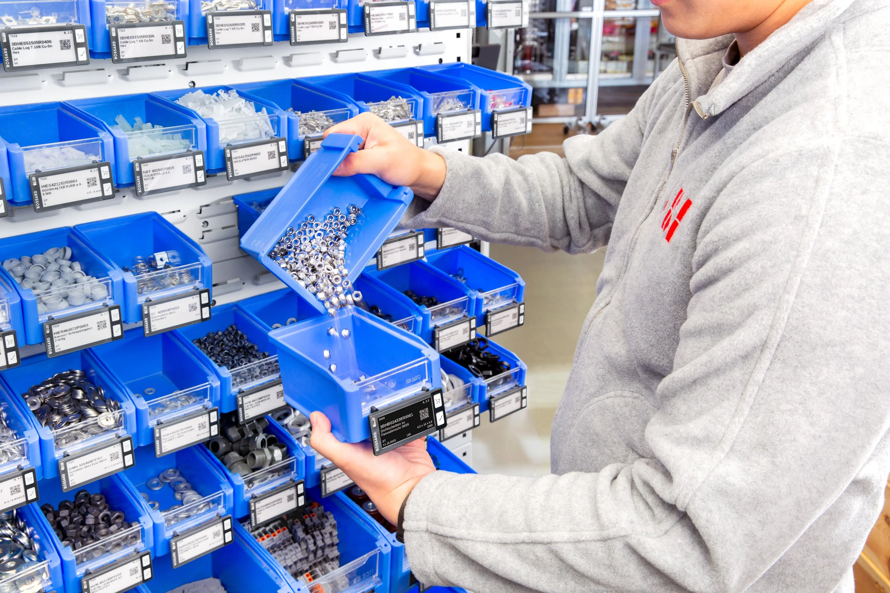 A man is refilling a SmartLabel Cloud bin by moving nuts from one bin to another. 