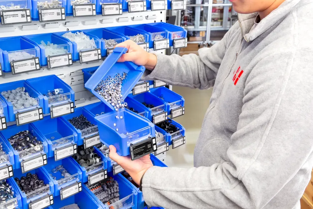 A man is refilling a SmartLabel Cloud bin by moving nuts from one bin to another.