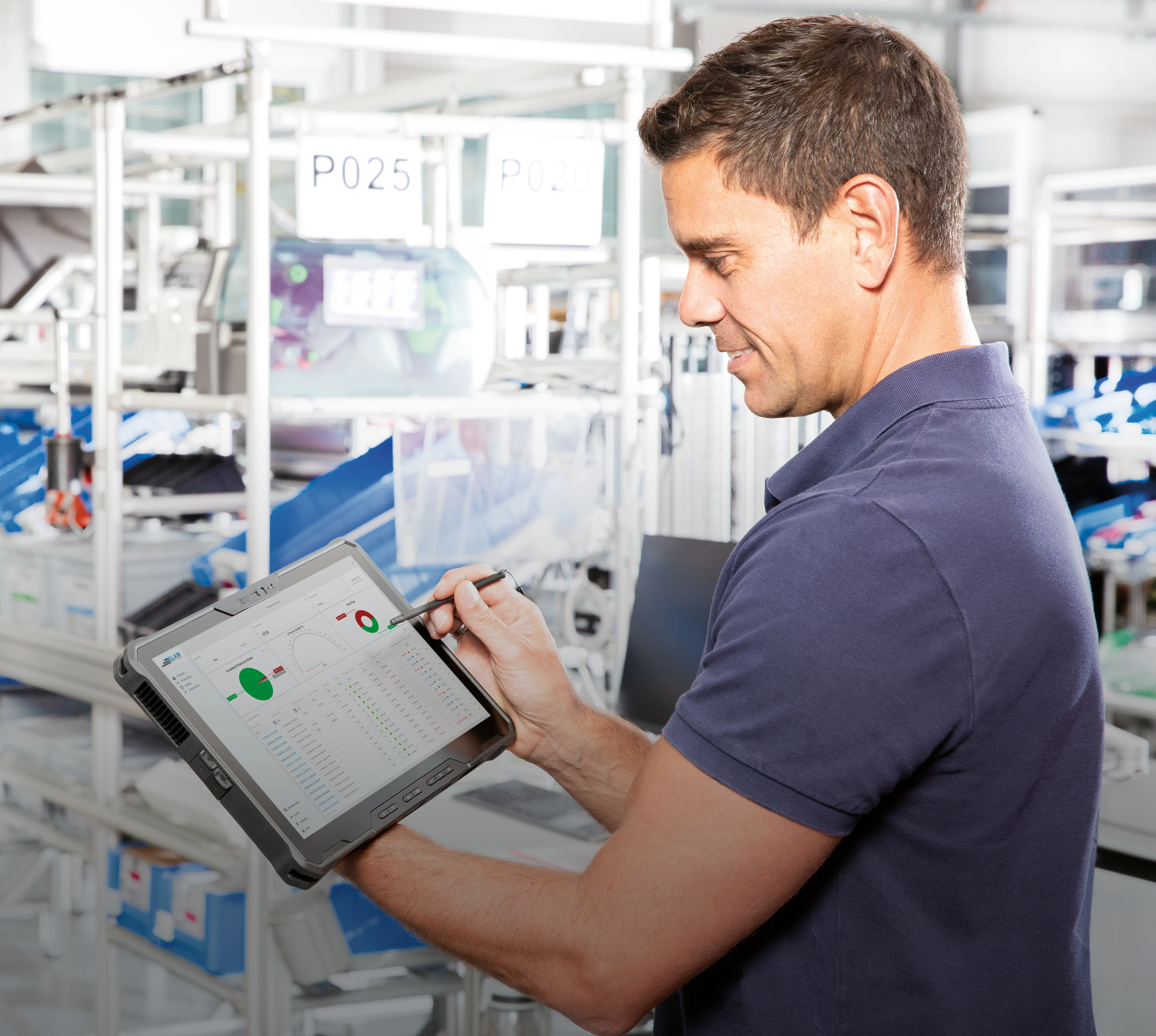 Smart Factory Assembly Guy with Tablet in his hands looking at the Dashboard with realt-time data