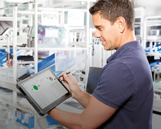 Smart Factory Assembly Guy with Tablet in his hands looking at the Dashboard with realt-time data