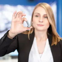 Woman in business attire holding a screw in her hand