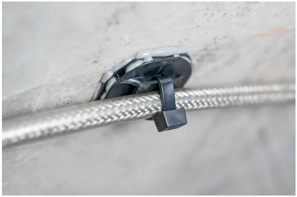 特写HellermannTyton粘合剂安装座，牢固固定电缆。